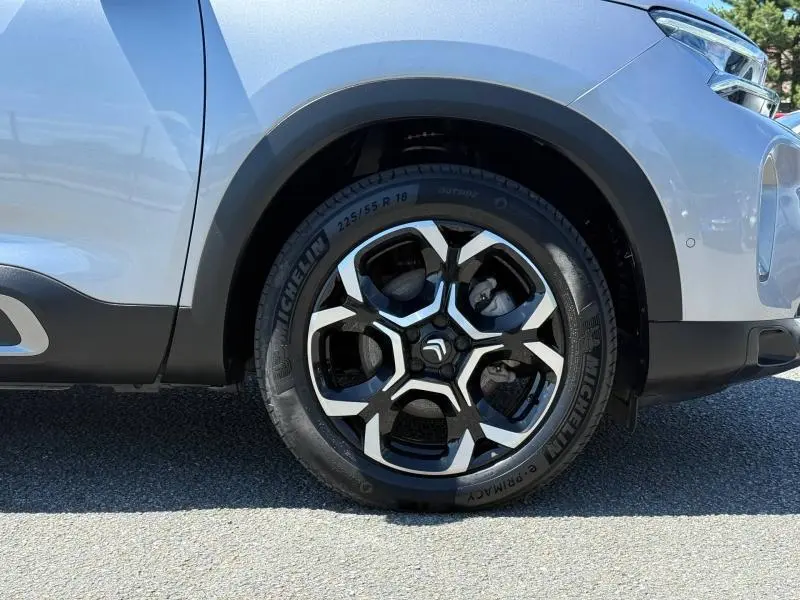 Gros plan sur la roue avant droite du Citroën C5 Aircross gris acier avec jante alliage noire et argentée.