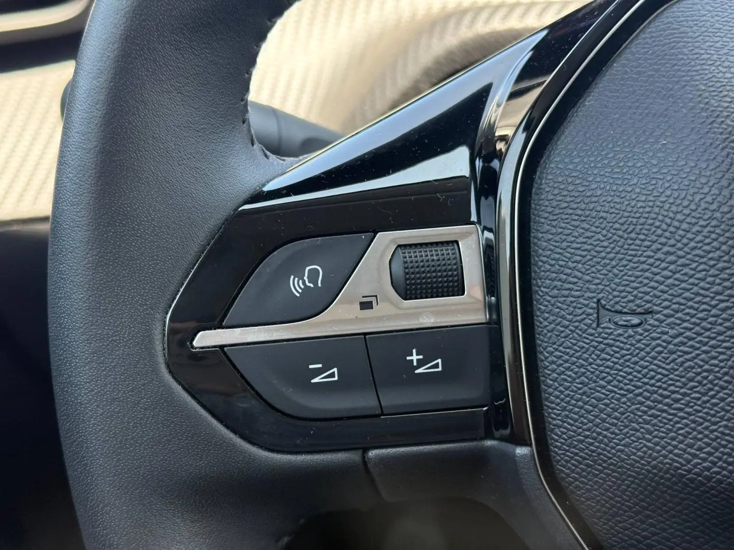 Gros plan sur les commandes audio au volant noir de la Peugeot 208 1.2 100ch Allure gris Artense.