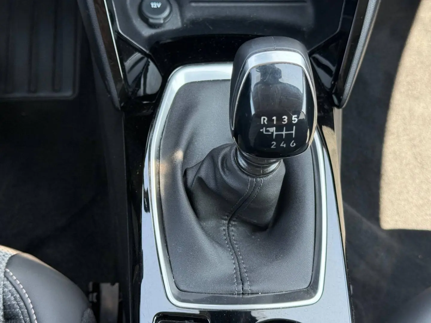 Gros plan sur le levier de vitesses manuel noir de la Peugeot 208 1.2 100ch Allure, entouré de garniture brillante.