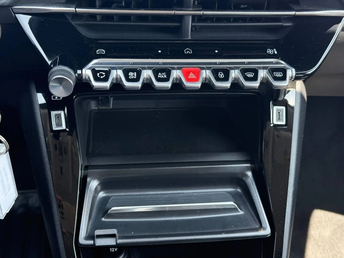 Vue rapprochée de la console centrale noire avec commandes climatisation et ports USB de la Peugeot 208 gris Artense 2025.