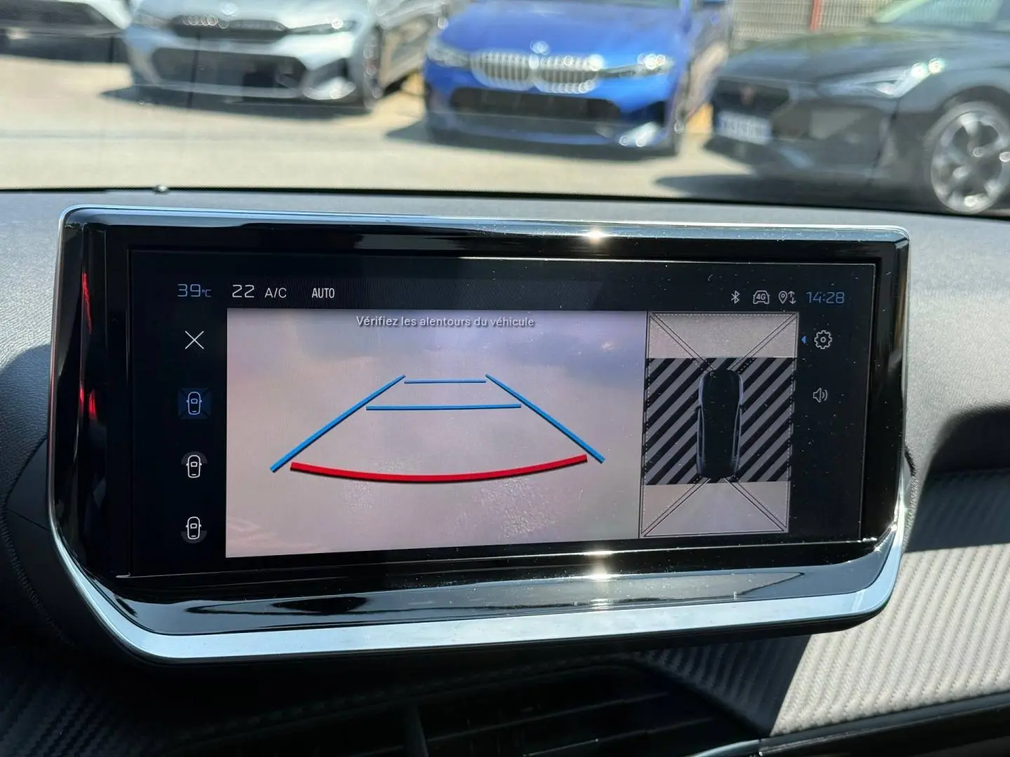 Écran tactile intérieur de la Peugeot 208 2025 montrant la caméra de recul avec vue 360° et tableau de bord noir.