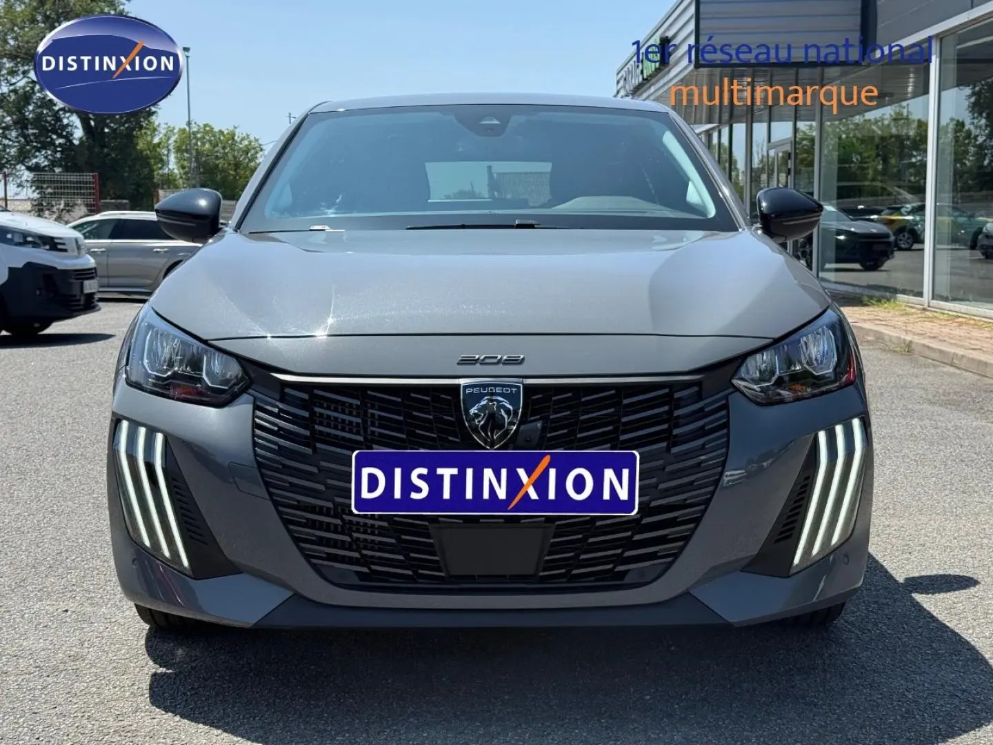 Vue frontale d'une Peugeot 208 gris Artense avec phares LED et calandre noire distinctive.