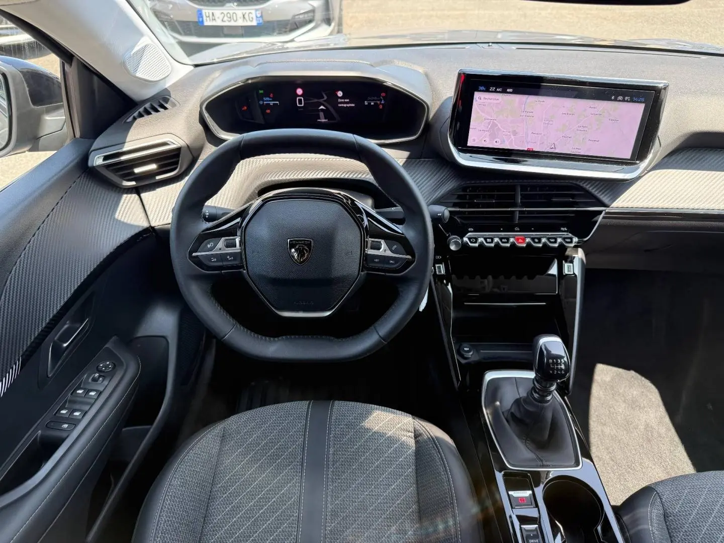 Vue intérieure avant de la Peugeot 208 1.2 100ch Allure, volant compact, écran tactile et levier de vitesse manuel.