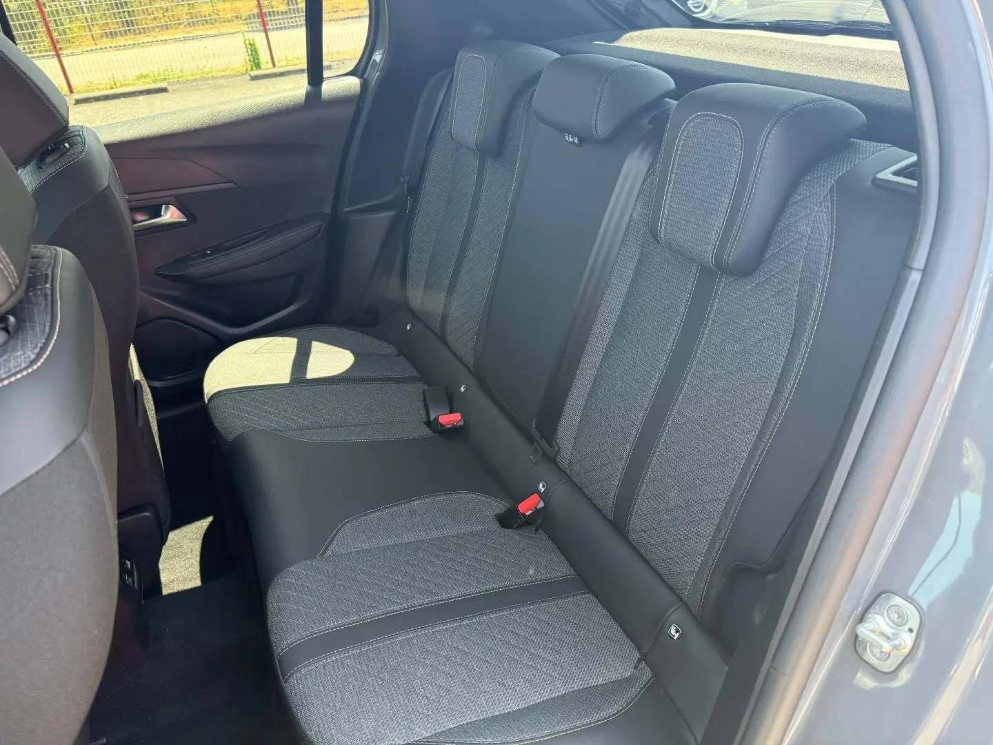 Vue intérieure côté droit sur la banquette arrière tissu gris et noir de la Peugeot 208 1.2 100ch Allure 2025 gris Artense.