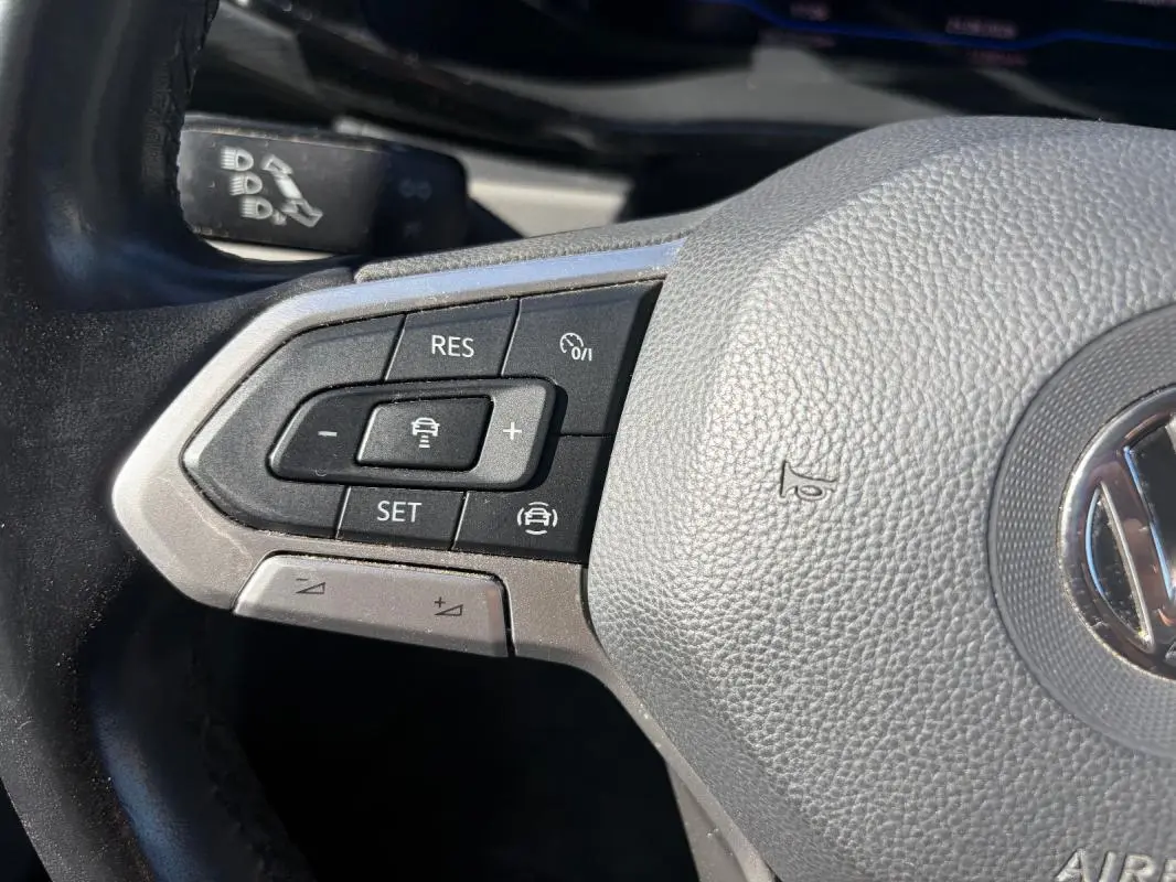 Gros plan sur le volant cuir du Volkswagen Transporter blanc, avec commandes de régulateur de vitesse visibles.