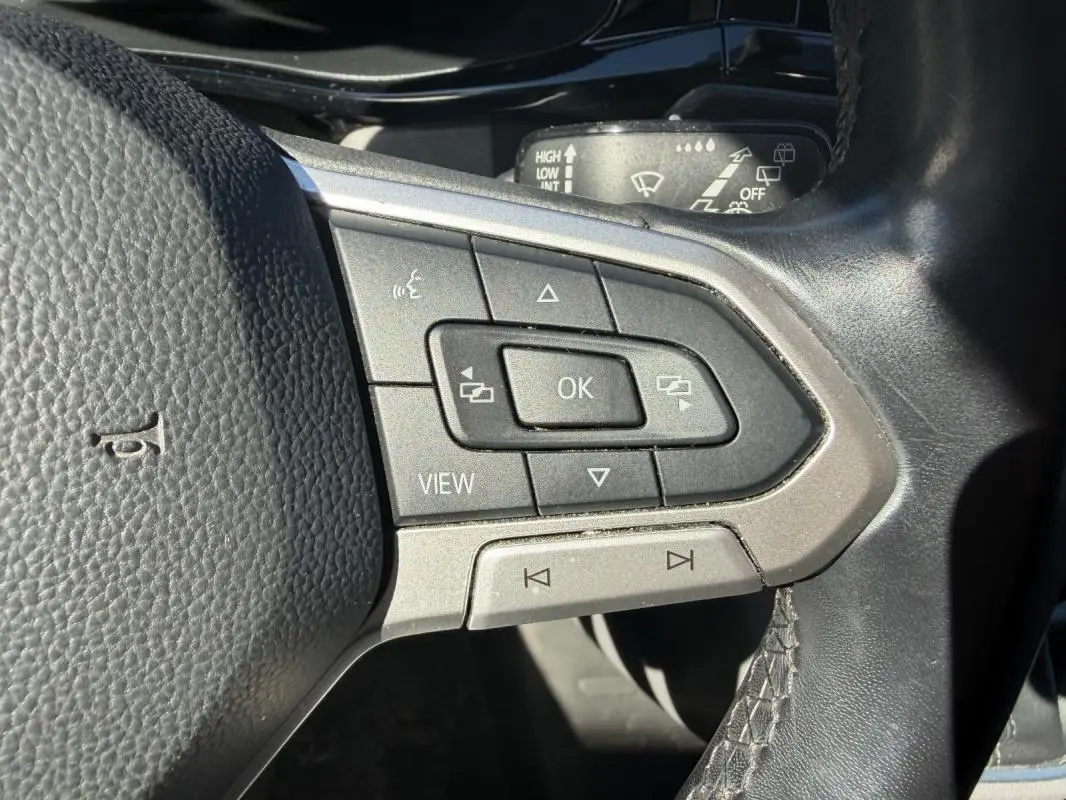 Gros plan sur les commandes multifonctions du volant cuir du Volkswagen Transporter blanc, version 2020.