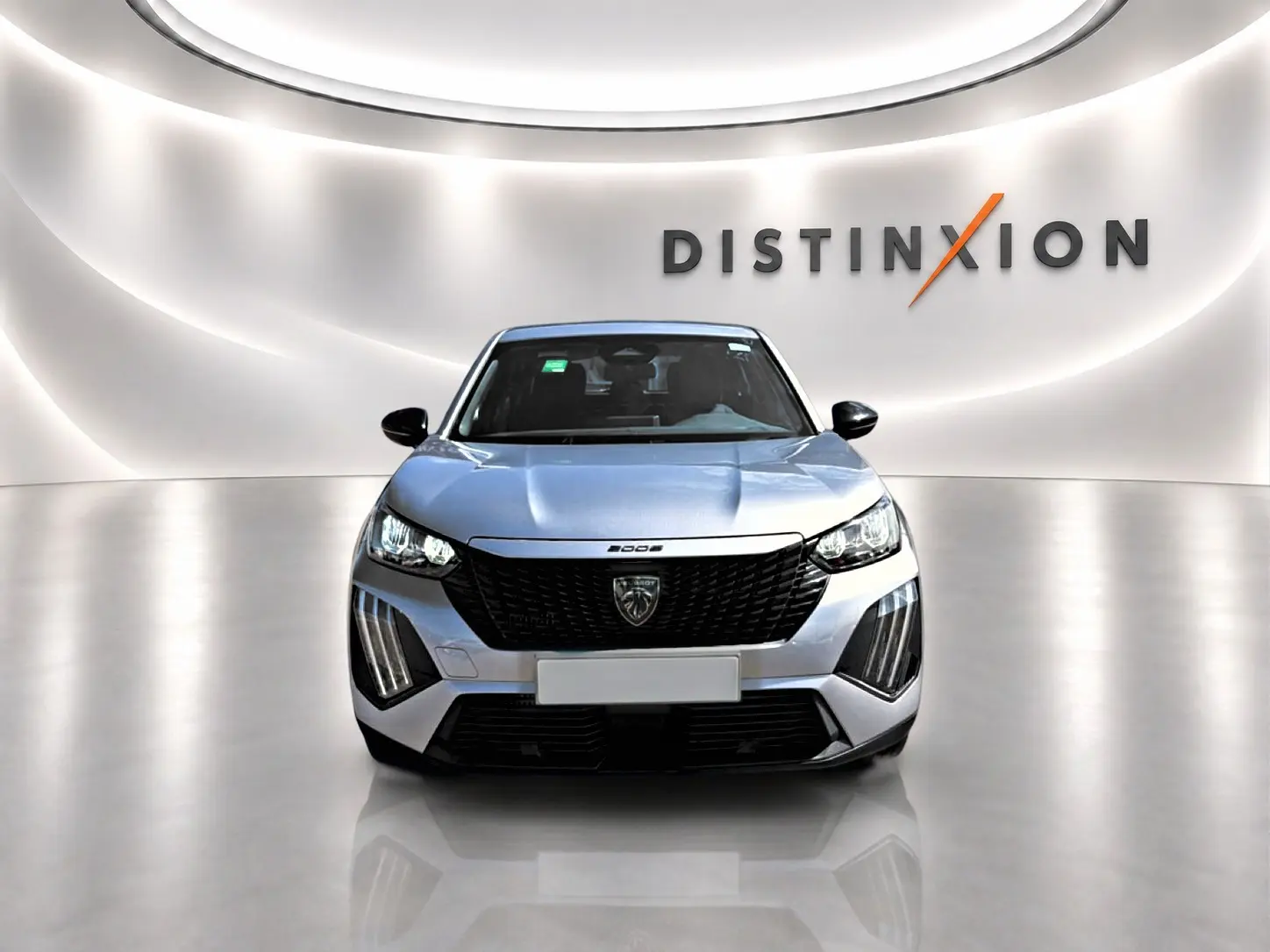 Vue frontale d'un Peugeot 2008 gris 2025 avec calandre noire et phares LED, dans un showroom lumineux.