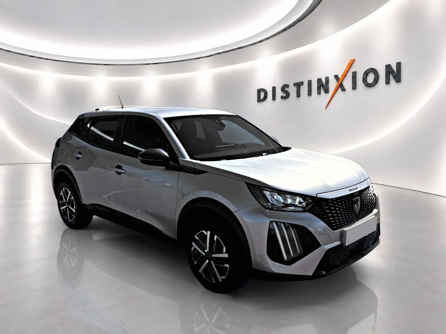 Peugeot 2008 gris en 3/4 avant droit, avec calandre noire et feux LED distinctifs dans un showroom lumineux.