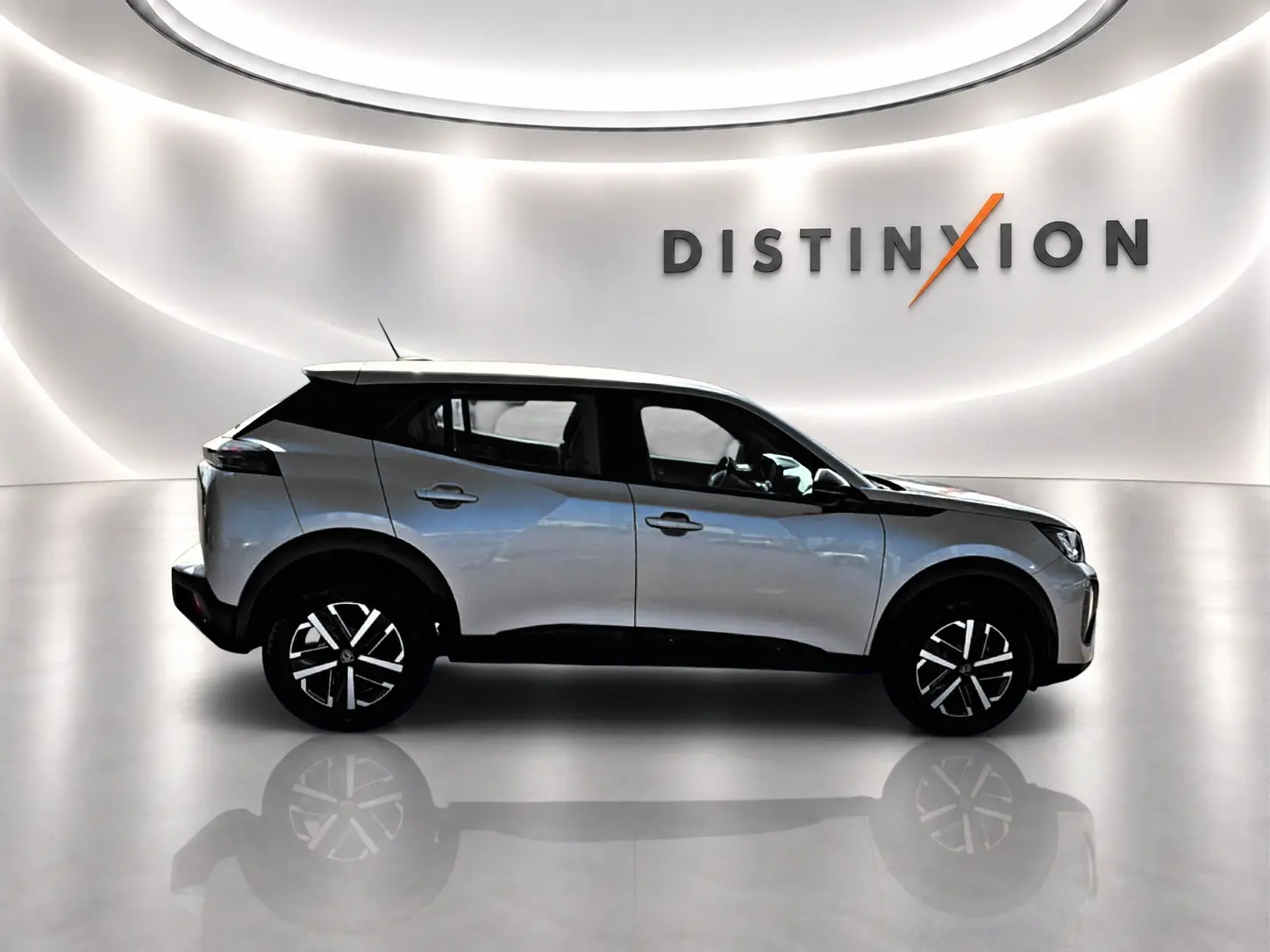 Peugeot 2008 gris en profil droit dans un showroom lumineux avec logo Distinxion en arrière-plan.