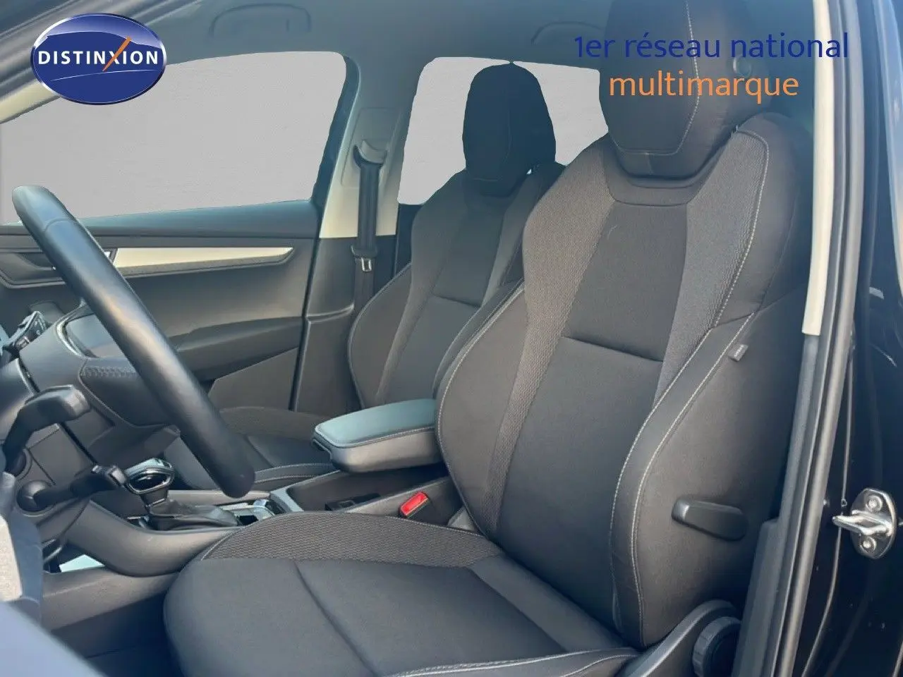 Intérieur côté conducteur d'un Skoda Karoq noir Magic Metal 2023, sièges tissu noir et tableau de bord moderne.