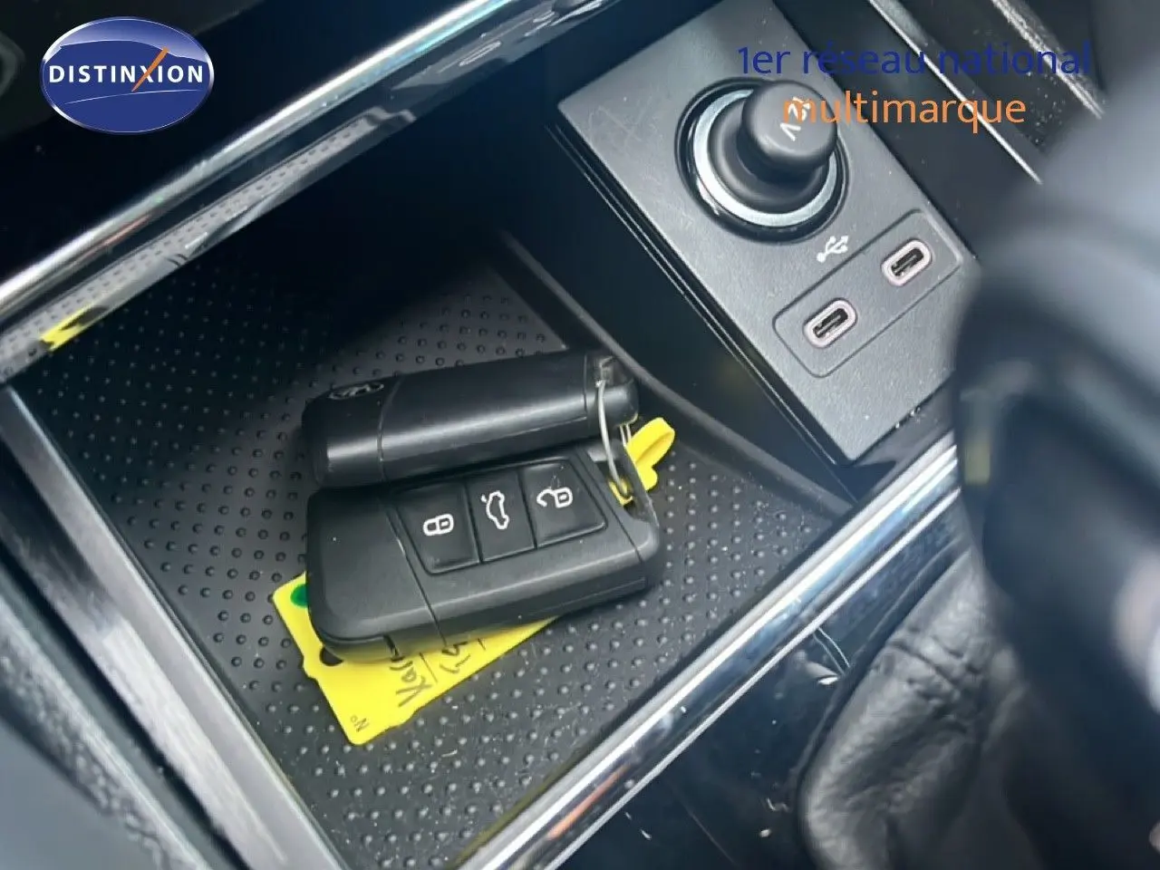 Gros plan sur la console centrale d'un Skoda Karoq noir avec clé de voiture et ports USB visibles.