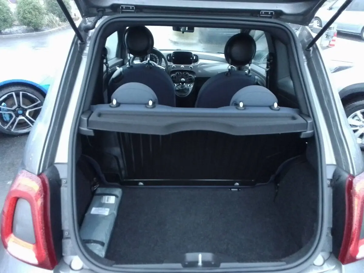 Coffre ouvert en vue arrière d'une FIAT 500 gris foncé, montrant l'intérieur et les sièges avant.