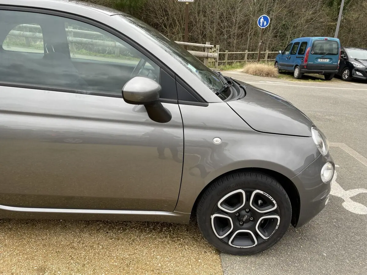 Vue de profil côté gauche d'une FIAT 500 Hybrid gris foncé avec jante alliage au design distinctif.