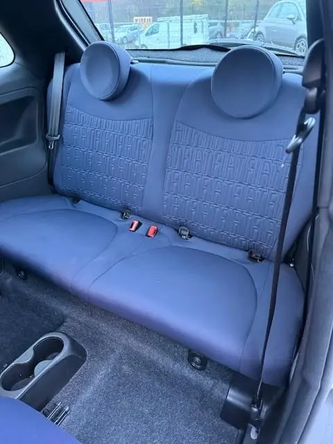 Vue intérieure arrière montrant la banquette arrière gris foncé avec motifs FIAT embossés de la Fiat 500 Hybrid 2022.