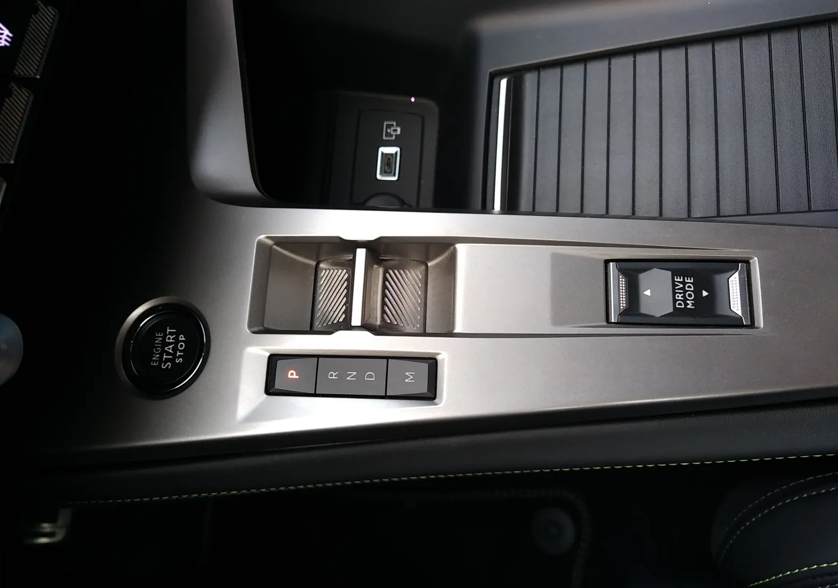 Vue rapprochée de la console centrale argentée du Peugeot 408 Hybrid 2024 avec boutons de boîte auto et mode de conduite.