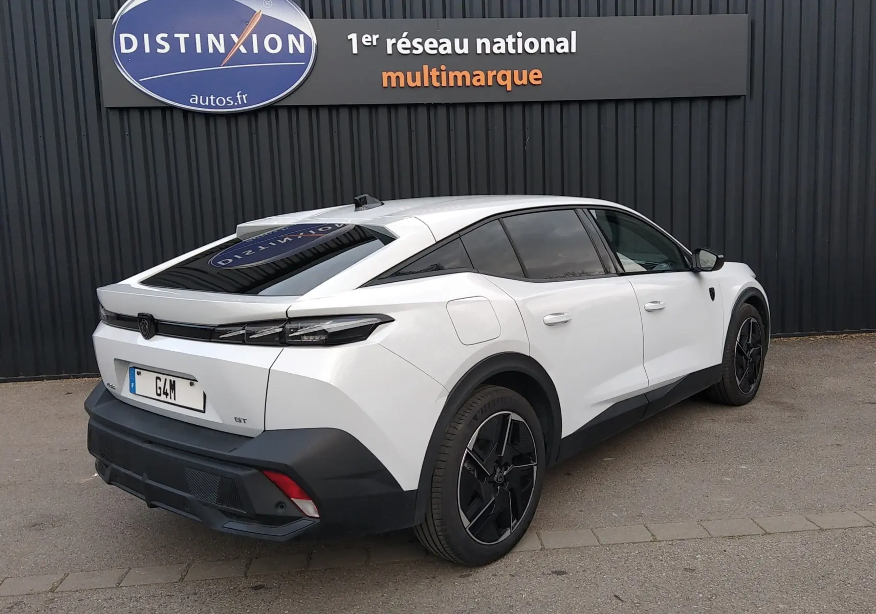 Vue 3/4 arrière droite d'une Peugeot 408 Hybrid blanche Okenite avec vitres teintées et jantes noires distinctives.