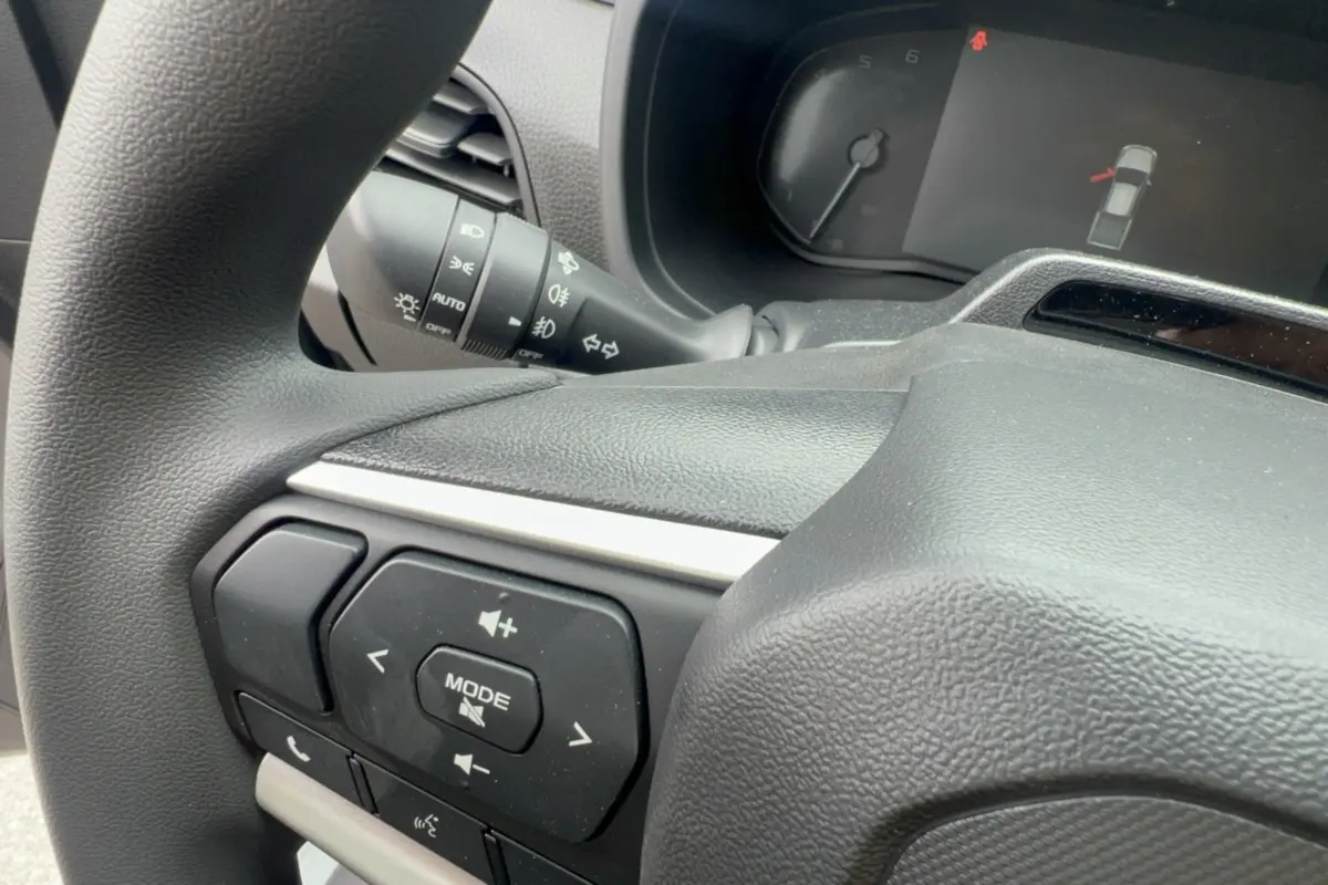 Gros plan sur le volant multifonctions noir de l'Isuzu D-MAX 2026 avec commandes audio et indicateur tableau de bord.