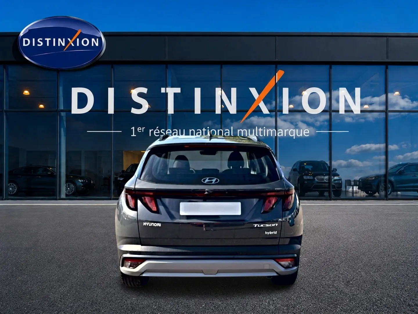 Vue arrière d'un Hyundai Tucson gris ecotronic hybride garé devant une vitrine avec logo Distinxion.