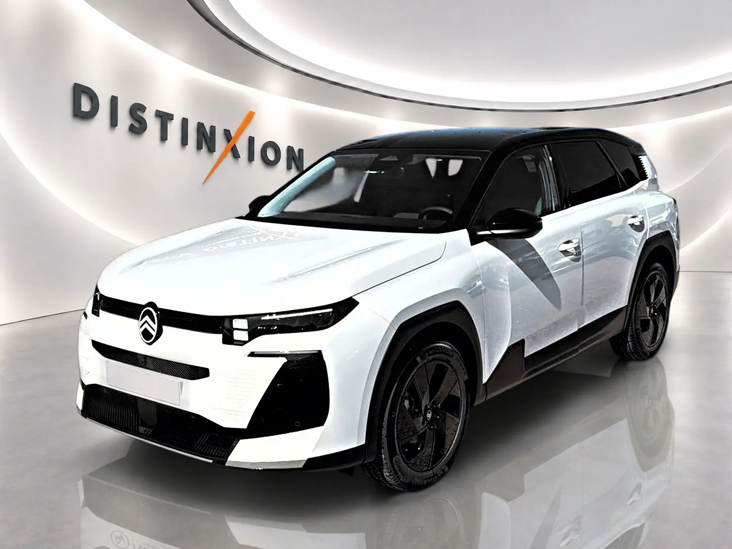 Vue 3/4 avant d'un Citroën C5 Aircross blanc à toit noir avec jantes alliage noires dans un showroom.