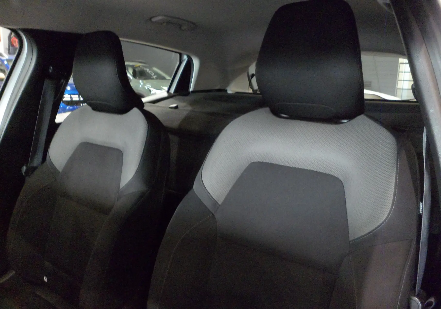 Gros plan sur les sièges avant en tissu gris et noir de la Renault Clio V Société Blanc Glacier, vue intérieure côté droit.