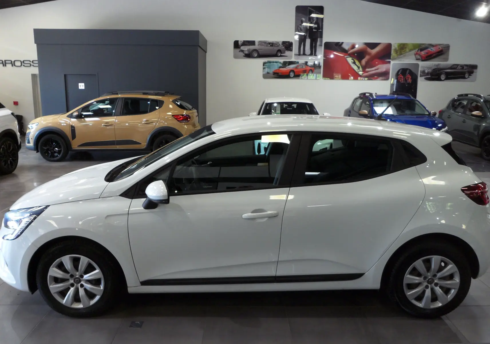 Profil côté gauche d'une Renault Clio V blanche Glacier en version Société, exposée en intérieur avec jantes alliage.