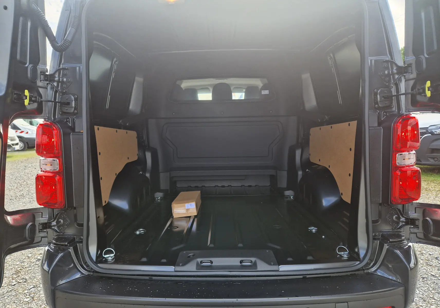 Vue arrière ouverte du Citroën Jumpy Gris Titane avec espace de chargement vide et panneaux latéraux en bois.