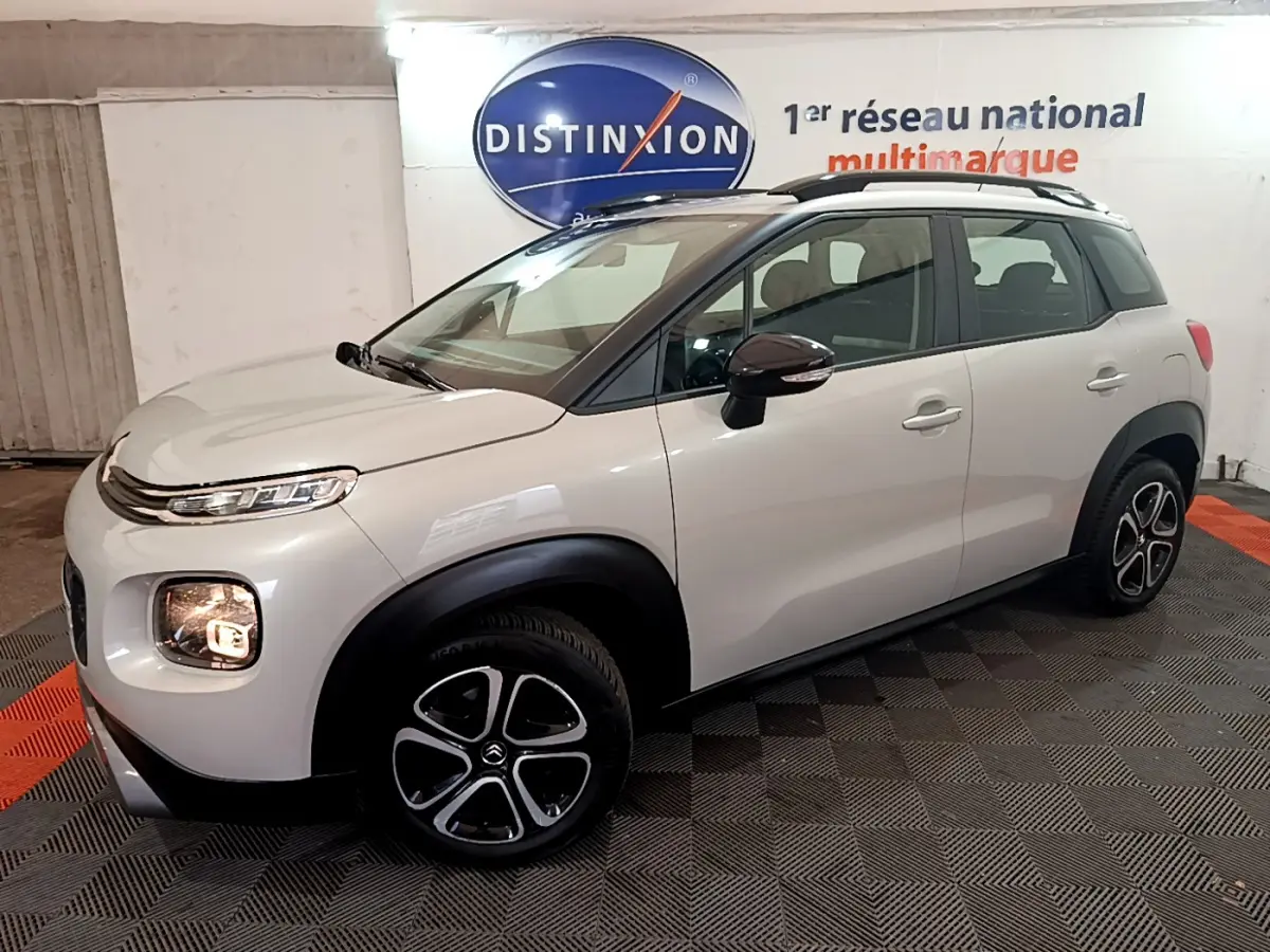 Citroën C3 Aircross blanc vue 3/4 avant droit, avec jantes alliage et barres de toit noires visibles.