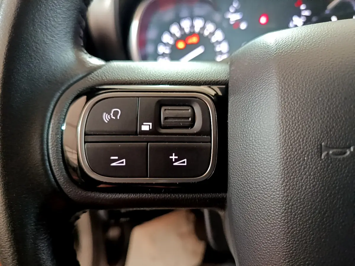 Gros plan sur les commandes multifonctions à gauche du volant cuir du Citroën C3 Aircross blanc de 2019.