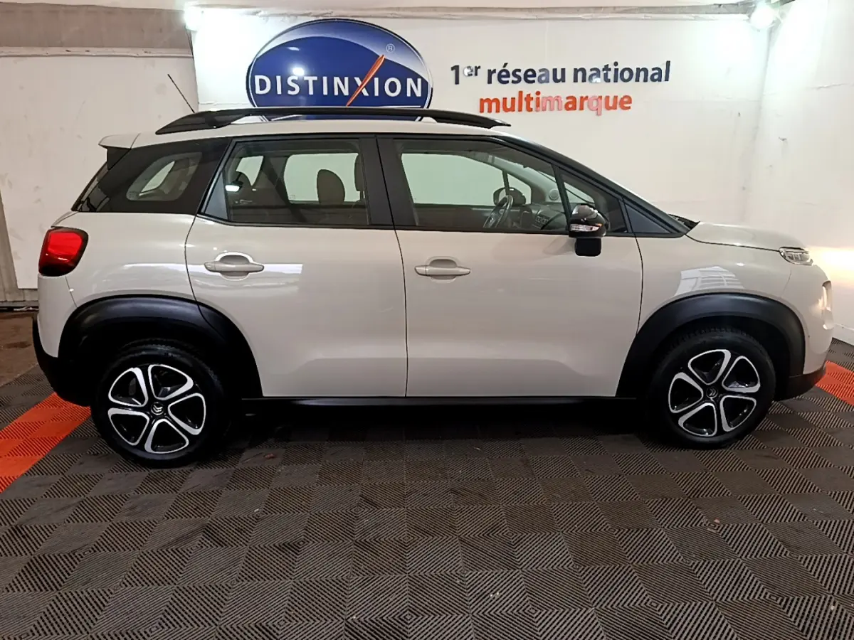 Profil côté gauche d'un Citroën C3 Aircross blanc 2019 avec barres de toit noires et jantes alliage distinctives.