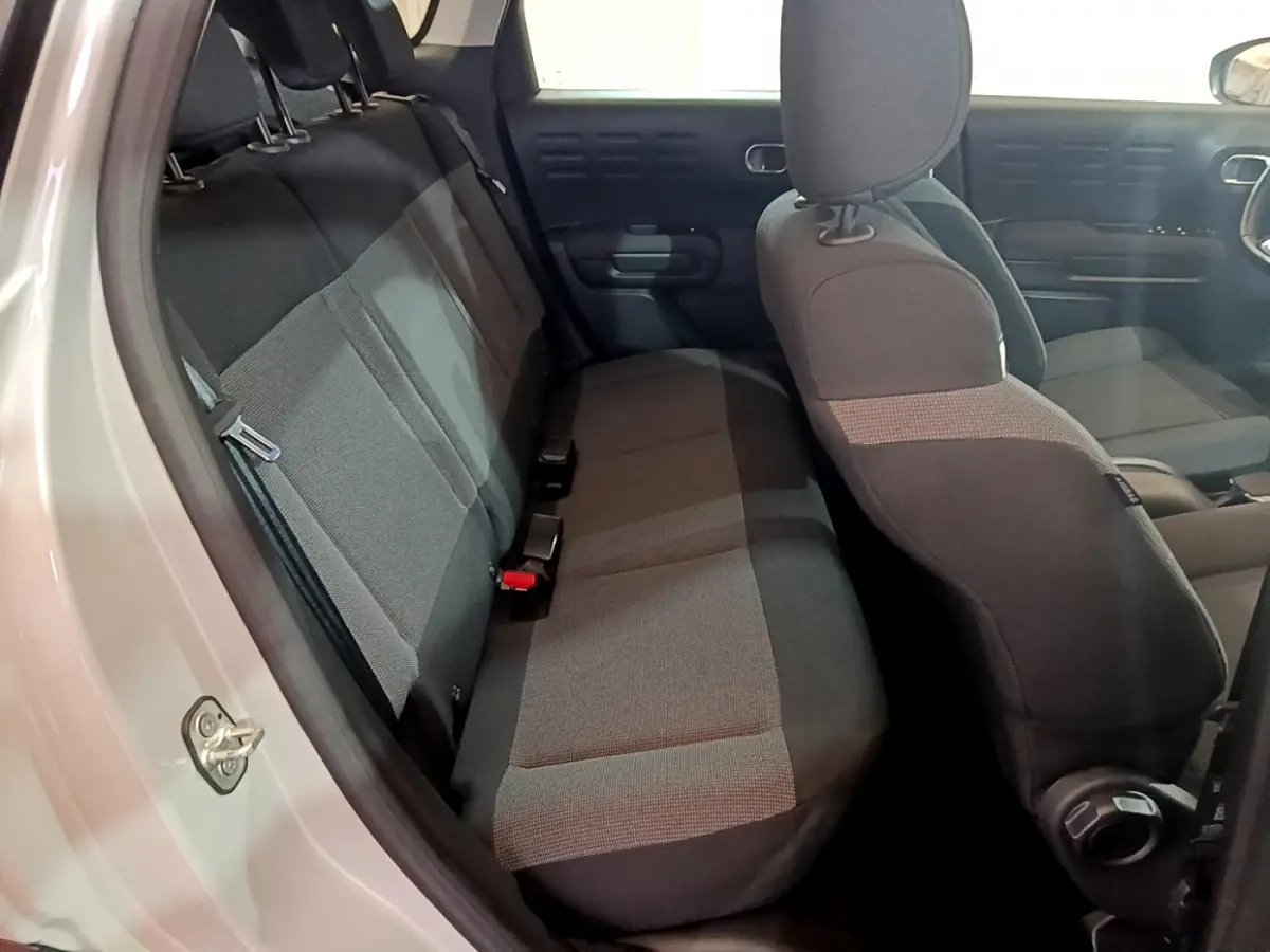 Vue intérieure côté gauche montrant la banquette arrière et les sièges avant noirs du Citroën C3 Aircross blanc.