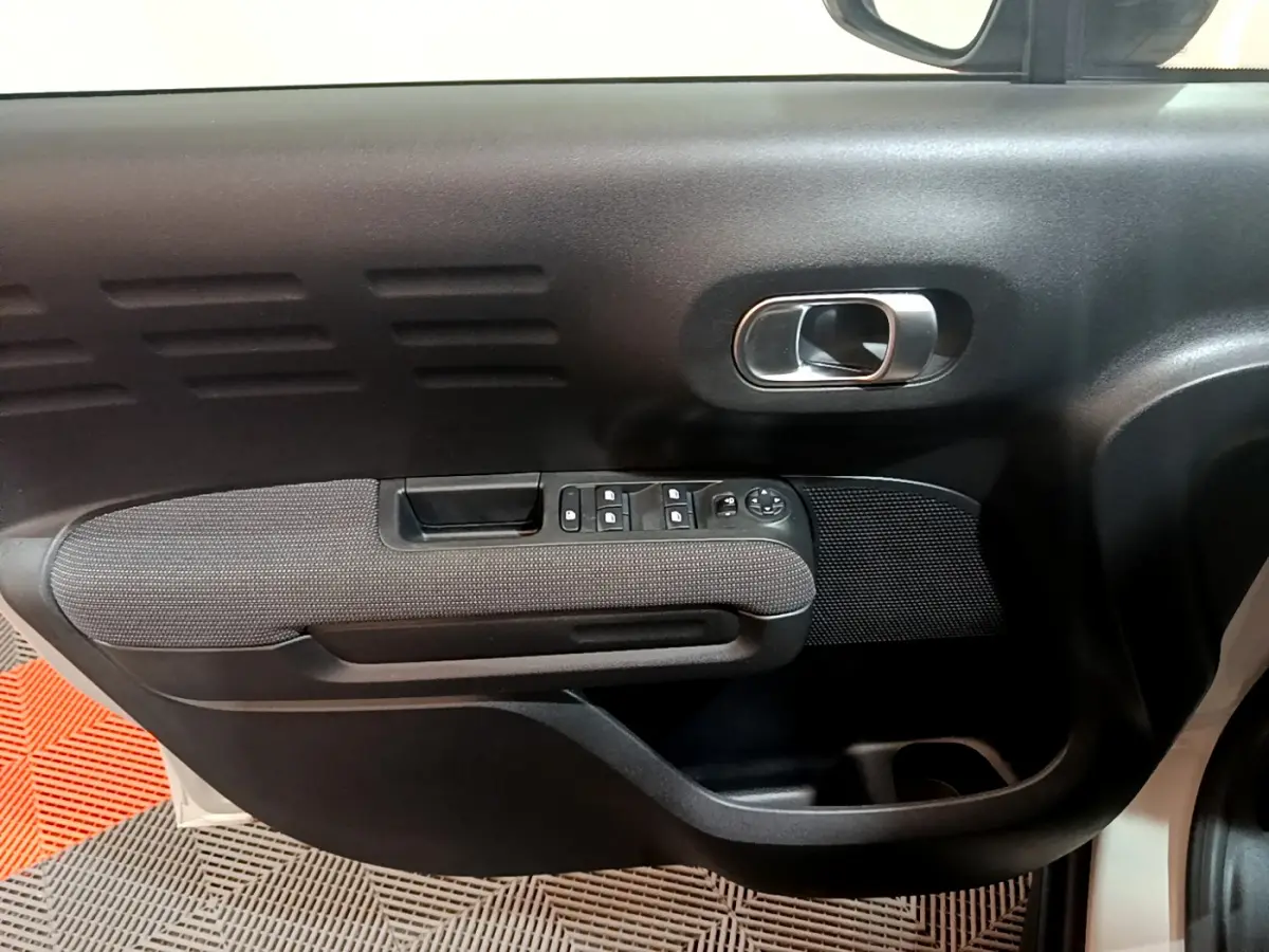 Gros plan sur la porte côté conducteur du Citroën C3 Aircross blanc, montrant la poignée et les commandes des vitres.