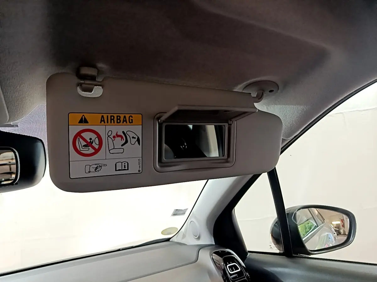 Détail du pare-soleil côté conducteur avec miroir et avertissement airbag dans l'habitacle blanc du Citroën C3 Aircross.