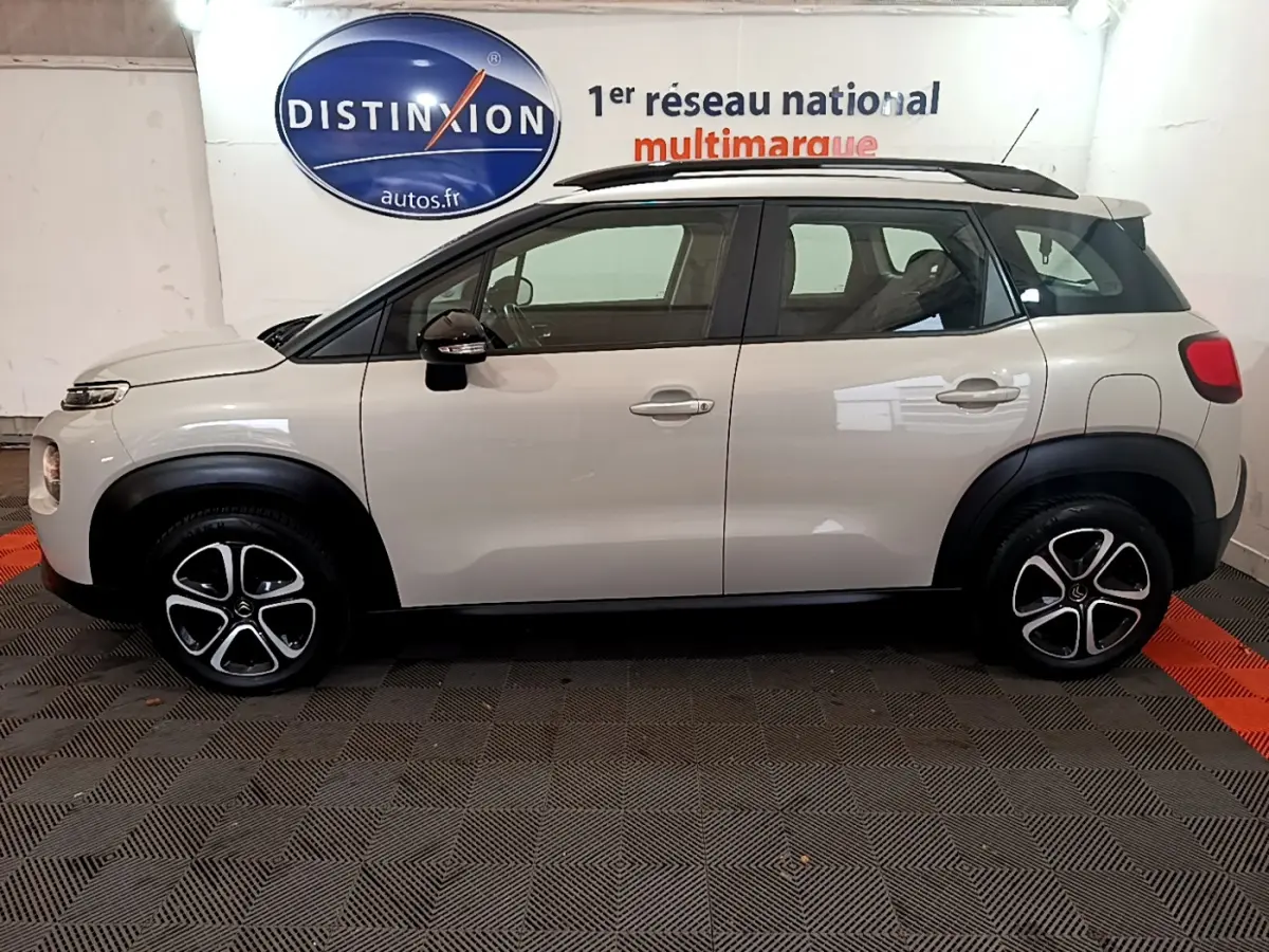 Profil droit d'un Citroën C3 Aircross blanc de 2019 avec barres de toit noires et jantes originales bicolores.