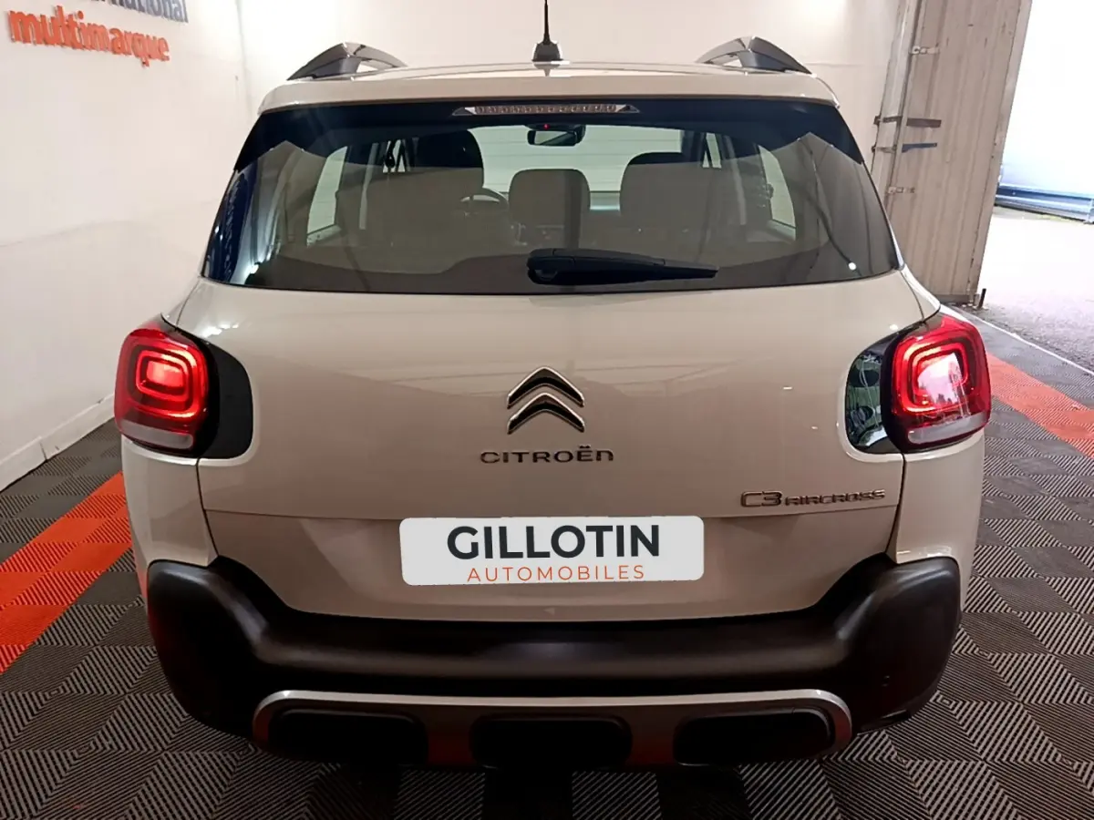 Vue arrière d'un Citroën C3 Aircross blanc avec feux arrière allumés et pare-chocs noir contrastant