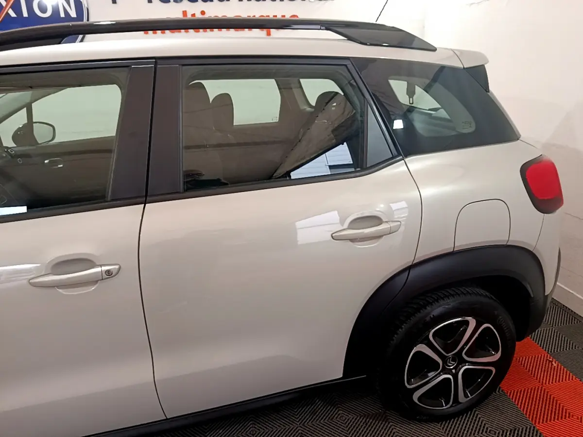 Vue latérale droite du Citroën C3 Aircross blanc, mettant en valeur les poignées de porte et les jantes noires au design distinctif.
