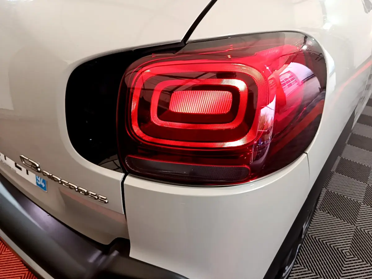 Gros plan sur le feu arrière droit rouge d'un Citroën C3 Aircross blanc, avec logo et partie arrière visibles.