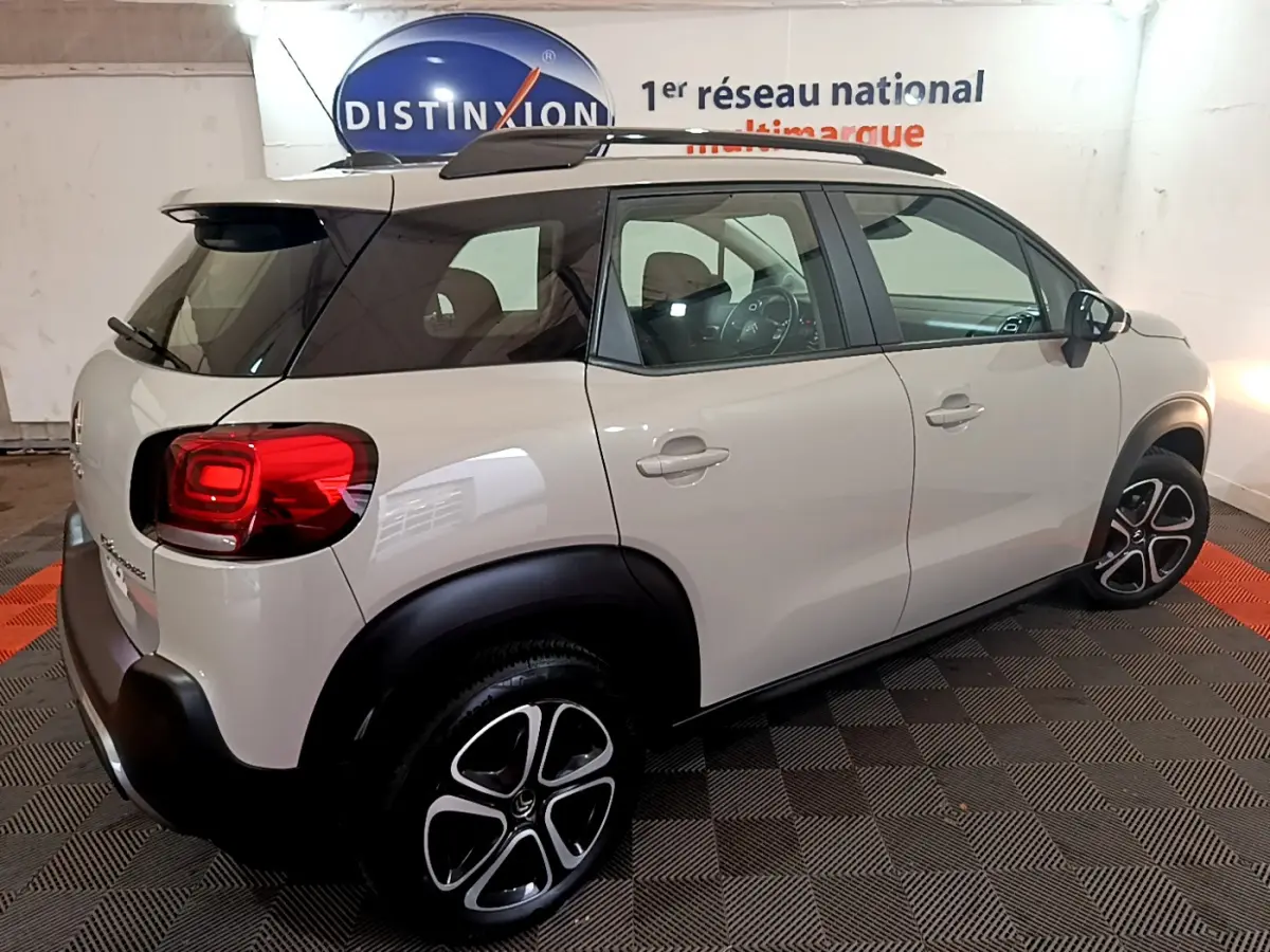 Vue 3/4 arrière droite d'un Citroën C3 Aircross blanc avec toit noir et jantes alliage distinctives.