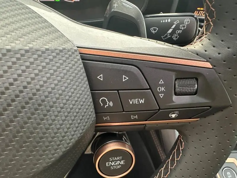 Gros plan sur les commandes du volant perforé et le bouton start/stop du CUPRA Formentor gris 2025, version diesel automatique.