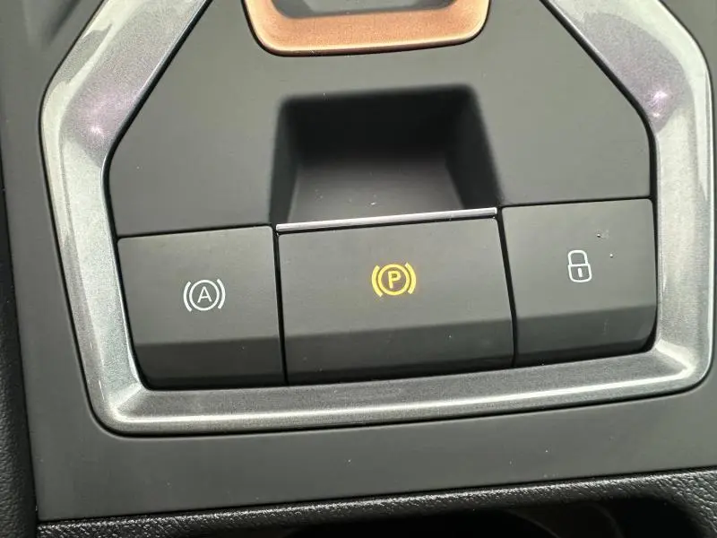 Gros plan sur les boutons de commande du frein à main électronique et verrouillage centralisé dans une CUPRA Formentor gris 2025.