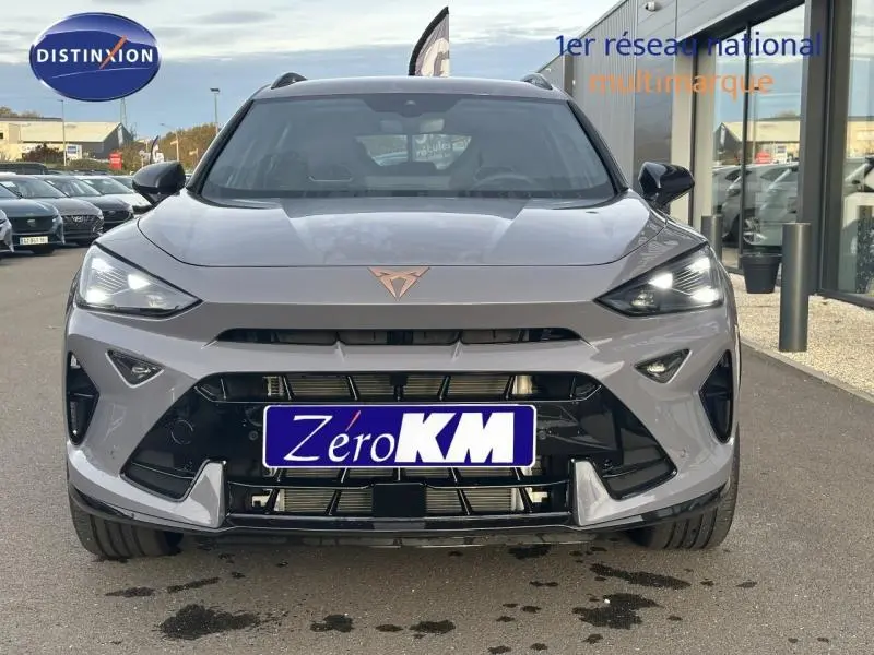 Vue frontale d'un CUPRA Formentor gris 2025 avec logo distinctif et phares LED allumés sur parking extérieur.