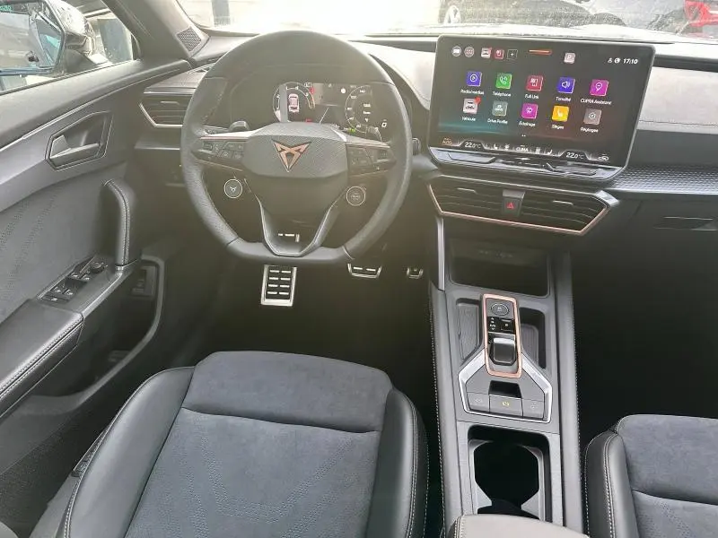 Vue intérieure avant du CUPRA Formentor gris 2025, mettant en valeur le volant multifonction et l'écran tactile central.