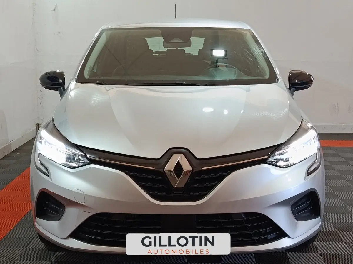 Vue frontale d'une Renault Clio Equilibre TCe 90 gris clair avec phares LED allumés en intérieur.