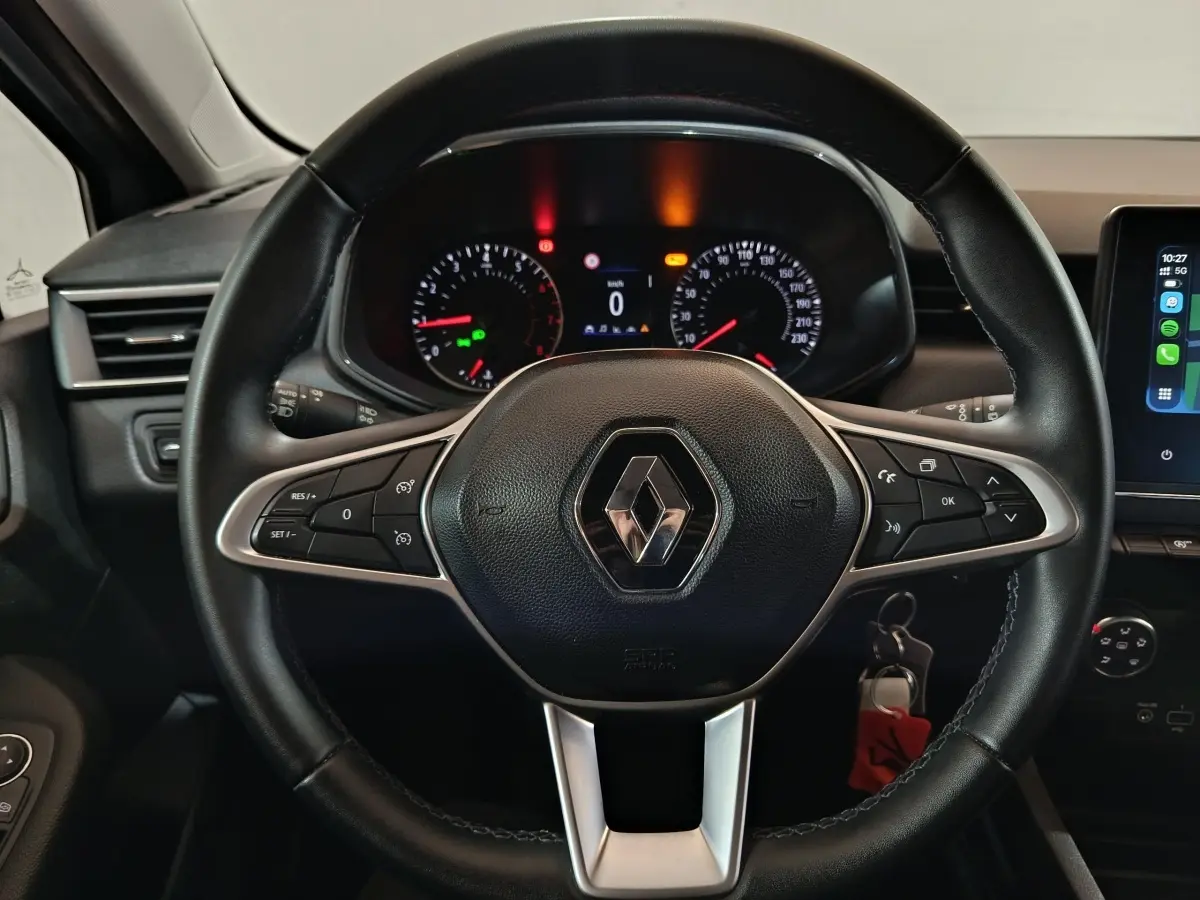 Vue rapprochée du volant cuir noir avec logo Renault, combiné d'instruments et écran tactile de la Renault Clio 2023.