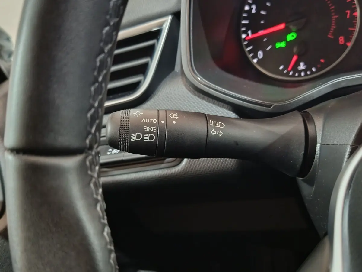 Gros plan sur la manette de commande des phares et clignotants à gauche du volant cuir d'une Renault Clio gris clair 2023.