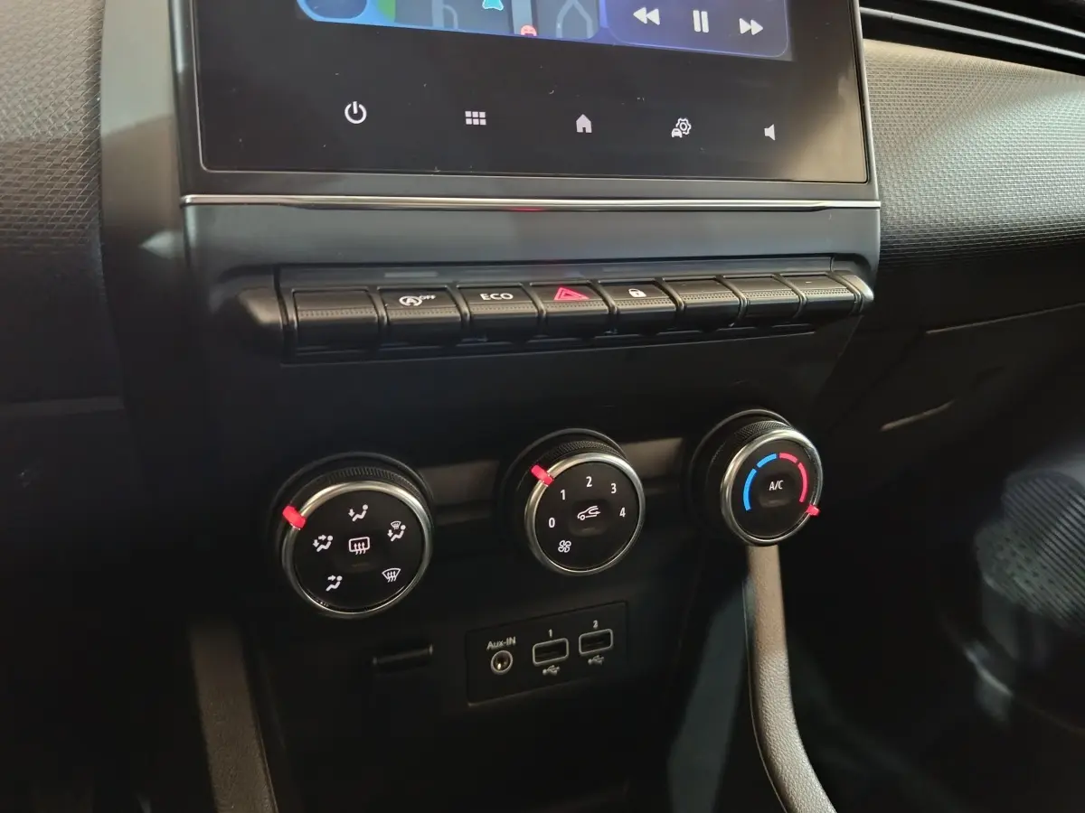 Vue rapprochée des commandes de climatisation et des ports USB sur le tableau de bord noir de la Renault Clio gris clair 2023.