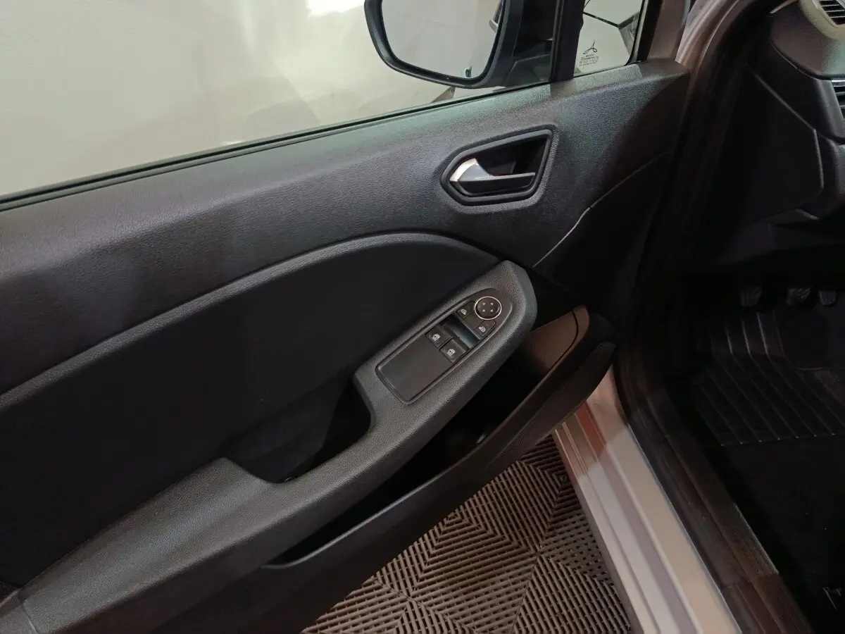 Intérieur côté conducteur de Renault Clio gris clair 2023, avec commandes électriques des vitres et rétroviseur.