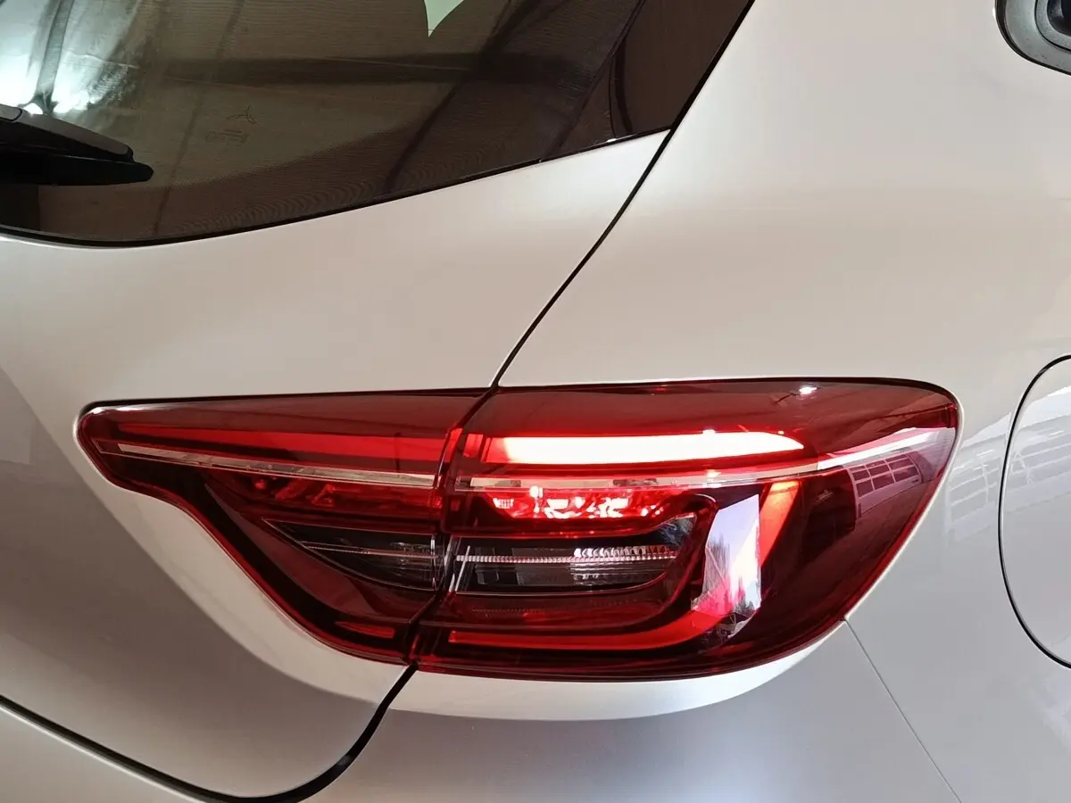 Gros plan sur le feu arrière droit rouge d'une Renault Clio 2023 gris clair, avec la trappe à carburant visible.