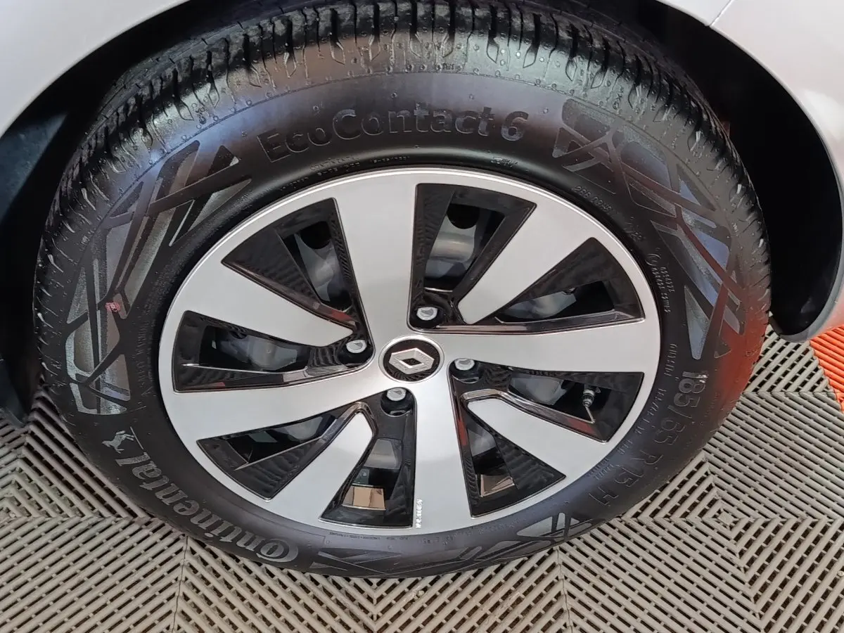 Gros plan sur la roue avant gauche de la Renault Clio gris clair, mettant en valeur la jante moderne bicolore et le pneu Continental.