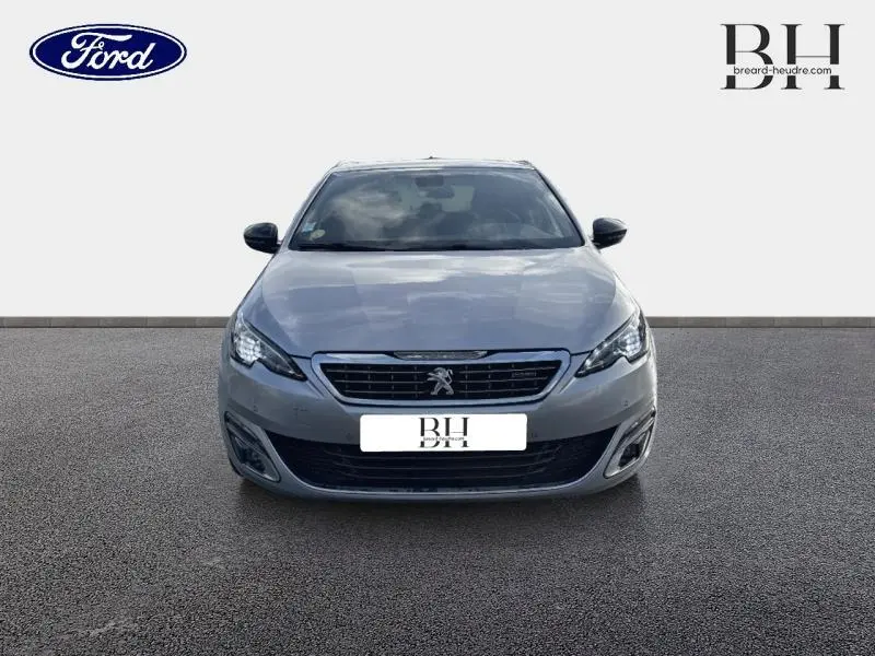 Vue avant d'une Peugeot 308 SW gris Artense avec calandre et phares LED distinctifs, sur fond neutre.