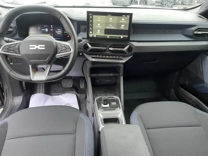 Vue intérieure avant du Dacia Duster 1.6 Hybrid gris schiste, avec tableau de bord moderne et écran tactile central.